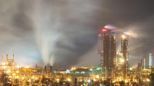 View of a large factory or plant in the light of night lighting A lot of smoke comes out of the factory's chimneys Pollution of the environment Toxic bad ecology