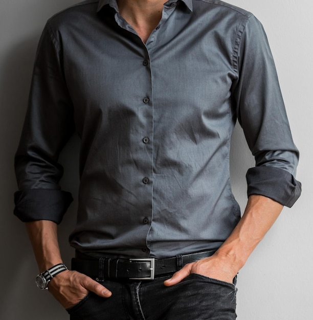 View of a man posing in a gray shirt leaning on the wall - professionalism concept