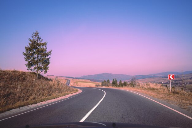 View of the mountain winding road from windscreen during sunrise