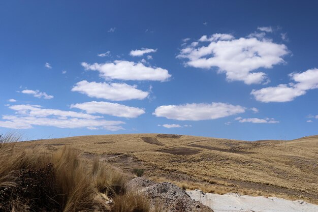 view of a mountainous landscape in Peru with dead vegetation and clear blue sky with clouds