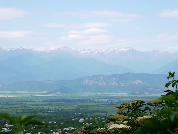 A view of the mountains in blue fog, snow lies on the peaks, the sky is in the clouds