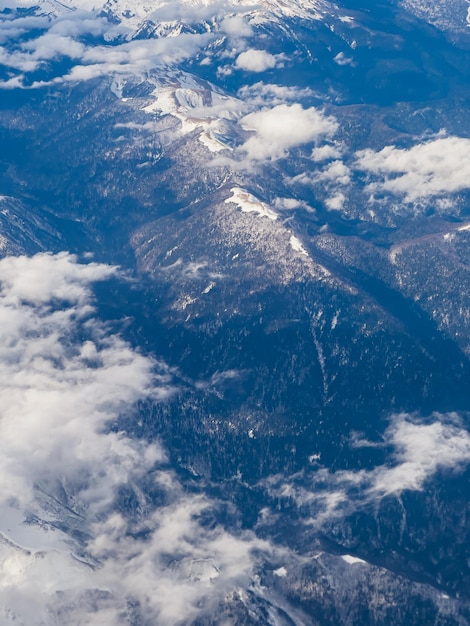 view of the mountains from the height of a flying airplane clouds mountains airplane wing blue sky d