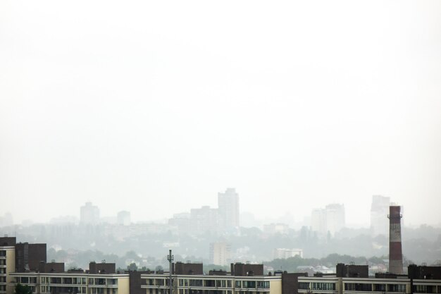 A view of the new houses against the background of the silhouettes of buildings in the misty sky. Photo from a bird's eye view of the drone.