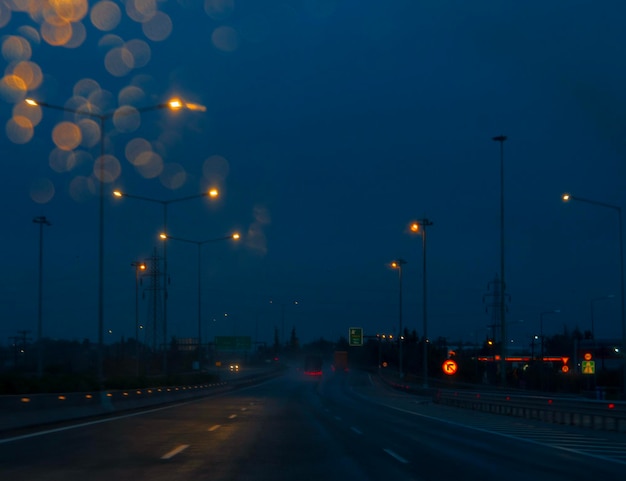 View of the night highway through the windshield of a car at speed in rainy weather