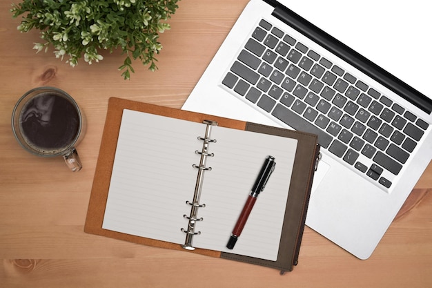 Above view notebook laptop computer coffee cup and houseplant on wooden desk