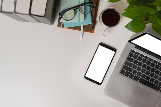 Above view office desk with mobile phone laptop and houseplant