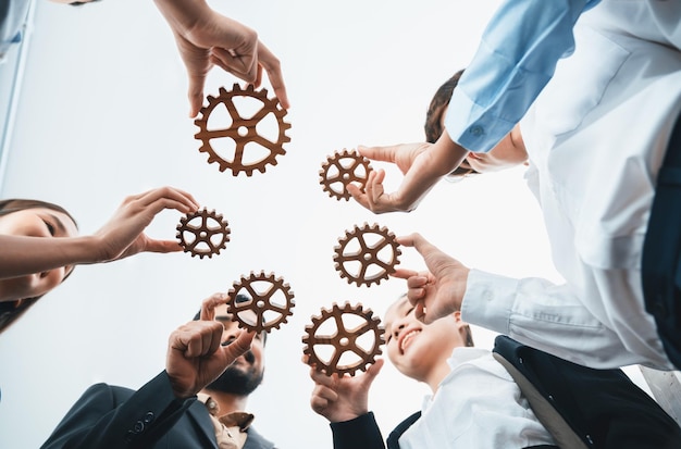 Below view office worker holding cog wheel as unity and teamwork in corporate workplace concept Diverse colleague business people as symbol of visionary system teamwork for business success Concord