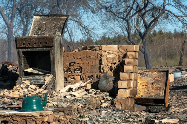 View of an old brick oven in a wooden house after a fire A destroyed house and dishes after a fire in a private house Old charred household appliances on the street