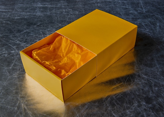 View of an open yellow gift box with packaging paper inside