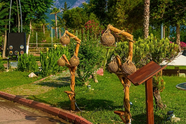 View of the path and wooden lanterns along the path in a green garden with green trees along the embankment in Kemer