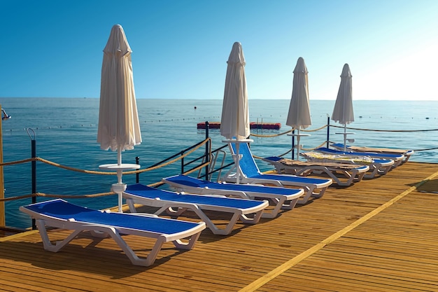 View of the pier with blue sun loungers and white umbrellas on the seashore in Kemer Turkey