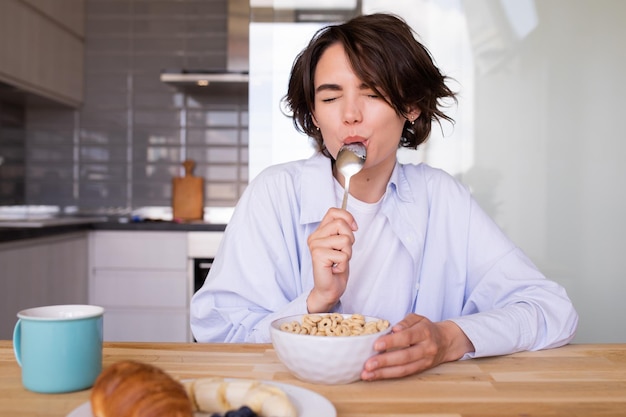 View of pretty woman tasting muslie with spoon at mouth