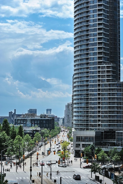 View of Queens Quay West in Toronto, Ontario. A skyscraper against the blue sky with white clouds.