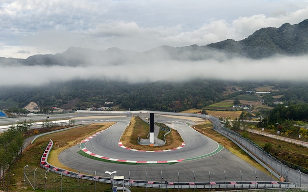 View of racetrack asphalt with curve of motor racing circuit in foggy valley