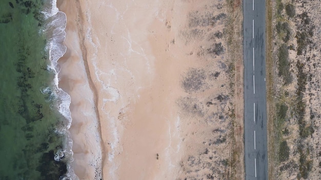 View of the road along the sea sandy coast from the drone Flying above empty road and beach