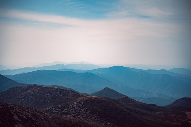 View of rocky mountains with plants against a gray sky in Itatiaia National Park Brazil