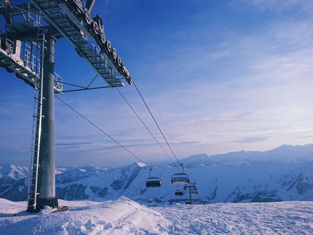 View of ski lift at ski resort with gorgeous snowy peaks at sunset