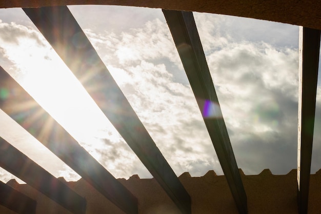 View of the sky and the sun through the beams on the roof