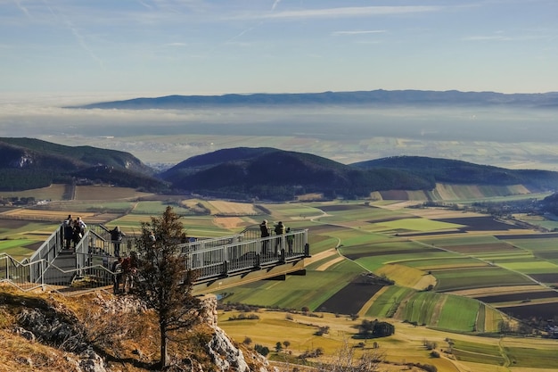 View to a skywalk and a wide green valley with fog