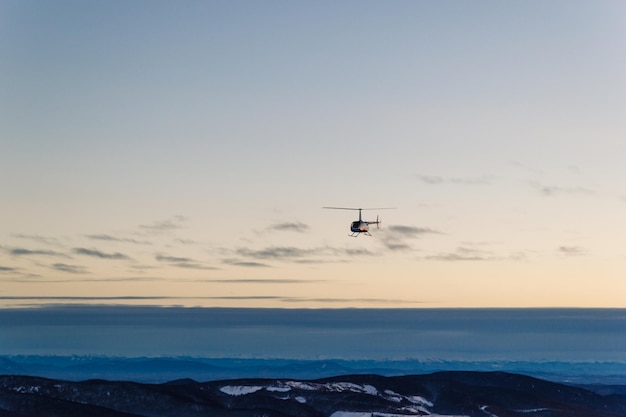 View of the slope of the ski resort at sunset with a riding snowmobile