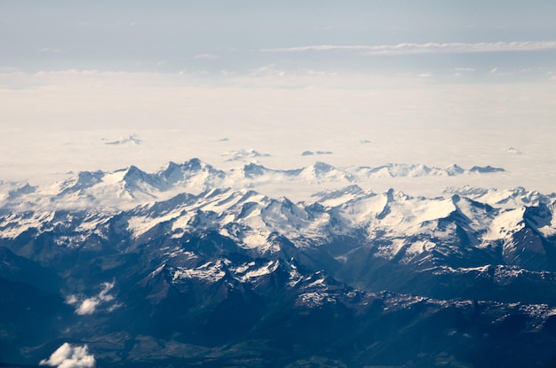 View of the snowy Swiss Alps from the heights above the white clouds.