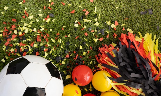 Above view of soccer ball and black yellow and red party favors