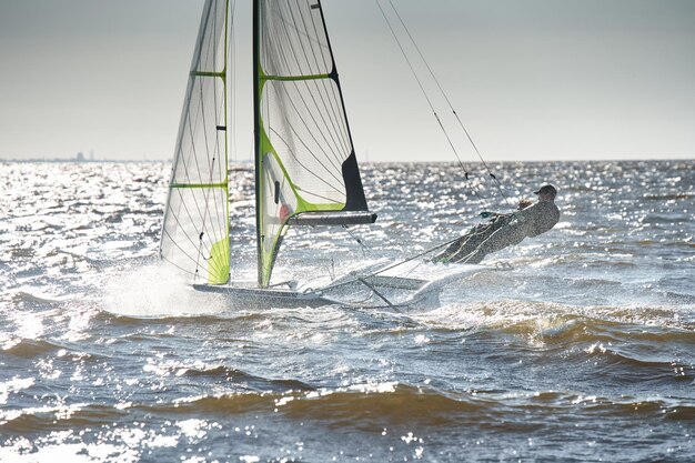 The view of sports sailboat is heeling at sunset athletes tilt the boat speed and spray reflection