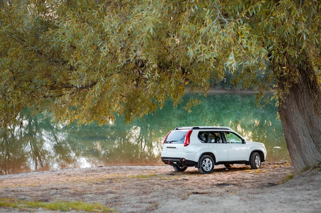 View of suv car at river beach on sunset. copy space