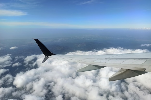 View through airplane window of commercial jet plane wing flying high in the sky Air travelling concept