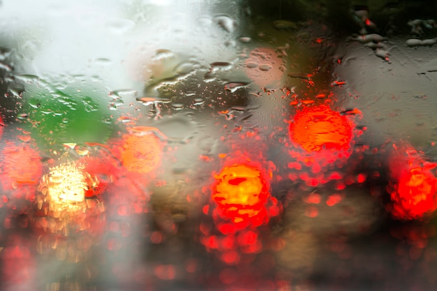 View through the glass of the car on the lights of cars in the rain. Blur on wet glass.