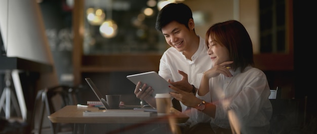 View through glass window of two businesspeople preparing their project with digital device