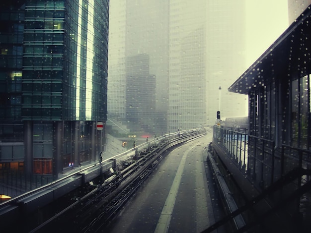 view through train window with raindrops to modern skyscrapers and railway