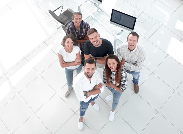 View the top a group of young professionals standing near the desktop and looking up