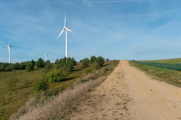 View of the windmill against the blue sky Wind turbines in the field or along roads Renewable energy source Use of natural resources for the benefit of humanity