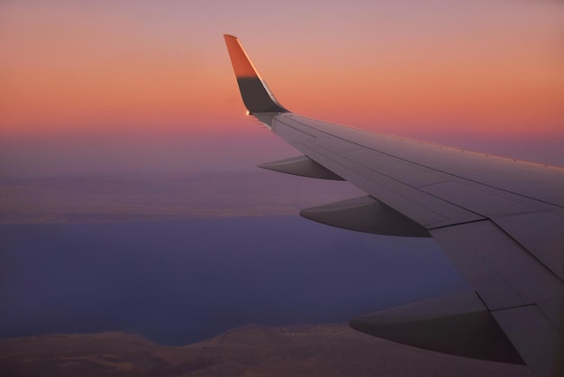 View to the wing of airplane in the sky during sunset