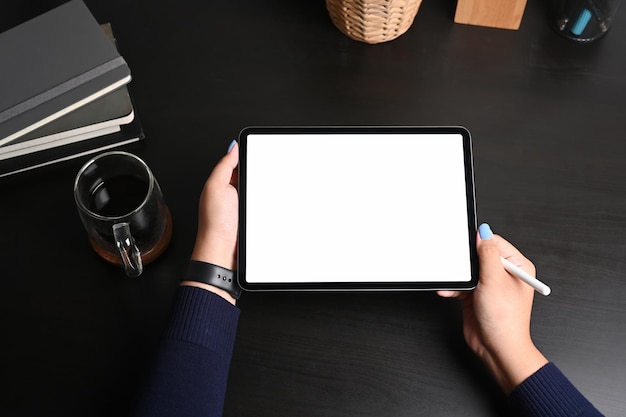 Above view woman holding digital tablet with blank screen on black wooden table