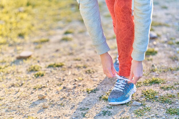 View of woman legs tying her shoelaces in the park