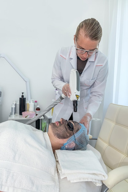 View of woman with cosmetic face mask lying on bed in spa center