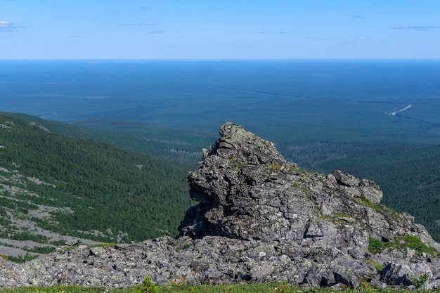 View of a wooded plain to the horizon from a mountain peak with bizarre rocks in the foreground