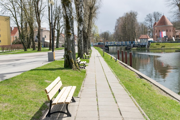 View of a wooden bench a water canal in a park in spring