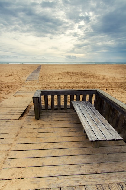 View of wooden passage in a long empty beach shoreline.