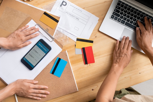 View of young female managers hands over workplace during checking information about online orders of clients and prepayment