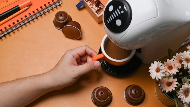 Above view young man making coffee with coffee machine on brown leather.