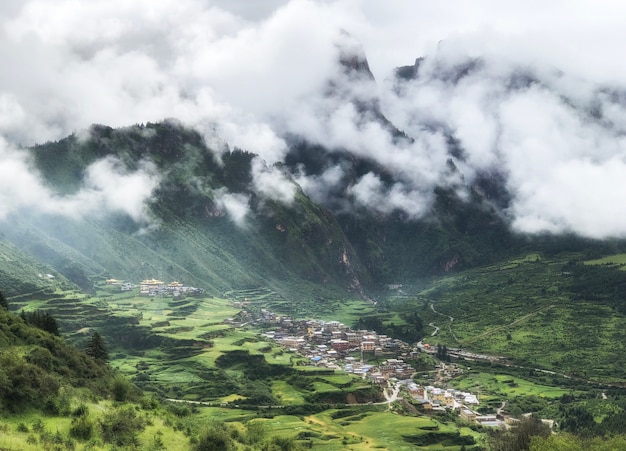 Village in the misty morning valley after rain.