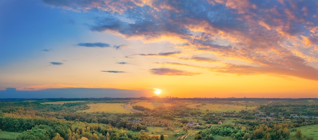 A village with small houses in the middle of a valley in the haze at sunset with a beautiful sky and yellow sun.