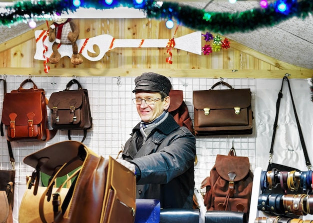 Vilnius, Lithuania - December 27, 2015: At one of the stalls man selling leather bags during the Vilnius Christmas market. The fair takes place each year from December till the start of January.