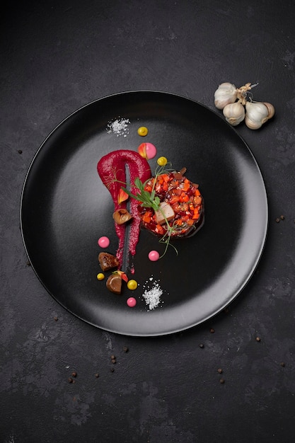 Vinaigrette salad on a black background, on a black plate with garlic