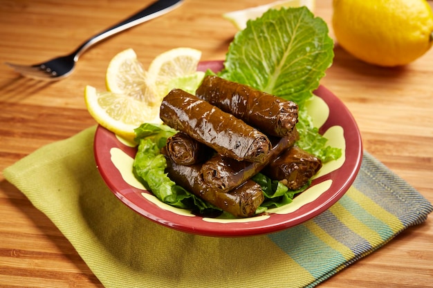 Vine Leaves rolls with lemon slice served in dish isolated on table side view of middle east food