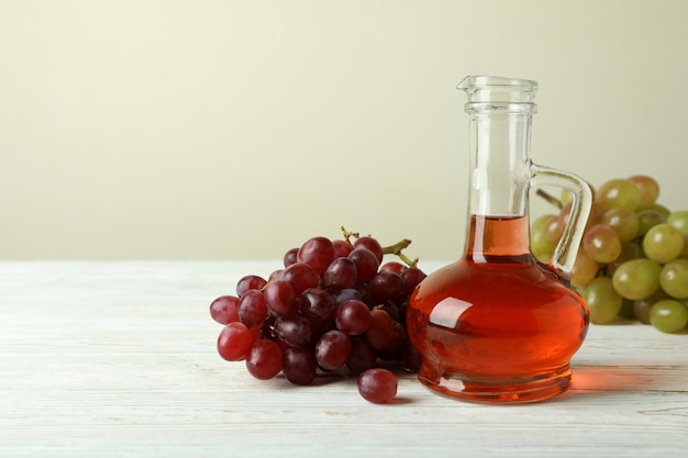 Vinegar and grape on white wooden table