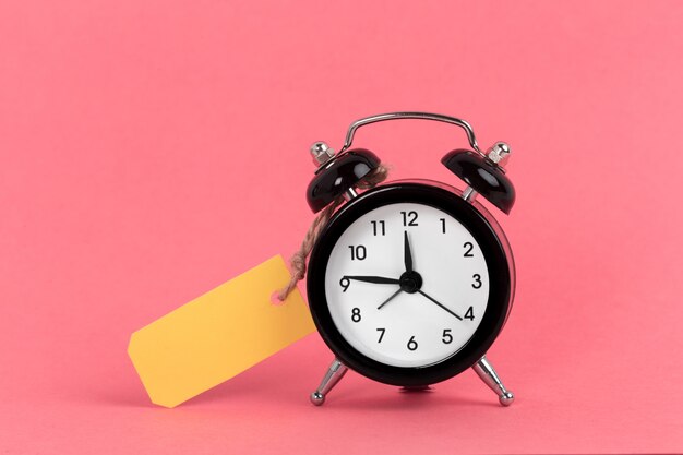 Vintage alarm clock on a bright pink surface